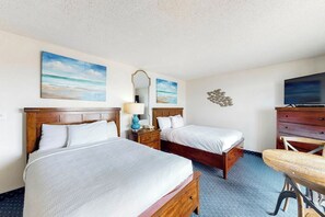 A hotel room with two beds, a desk, a television, and artwork on the walls. - Bay Watch Resort 1001 (North Myrtle Beach)