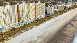 Ein Strandhotel mit mehreren Hochhäusern, einem Sandstrand und einem Poolbereich.