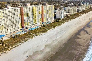 Ein Strandhotel mit mehreren Hochhäusern, einem Sandstrand und einem Poolbereich.