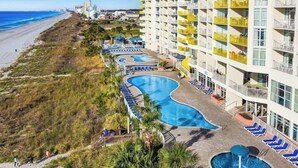Un resort con piscina, sillas de descanso y vista al mar.
