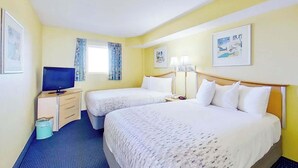 Una habitación de hotel con dos camas, un televisor, un escritorio y un cesto de basura.