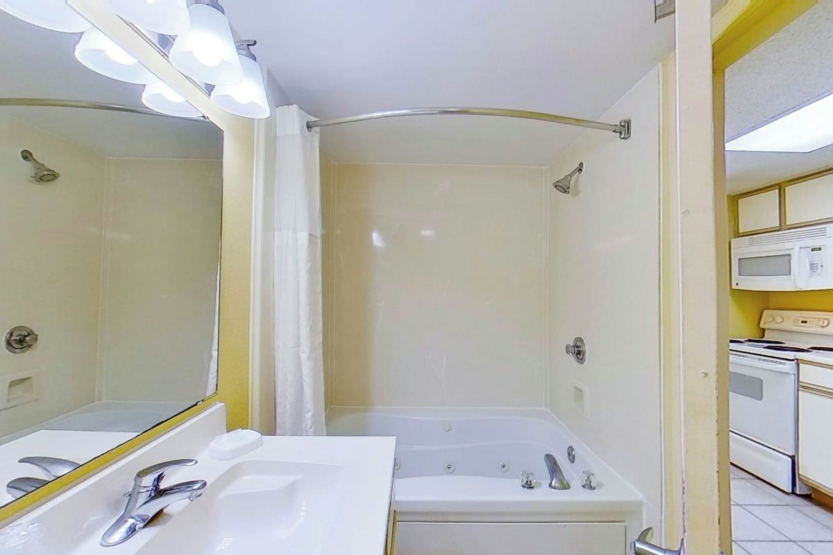 Un bagno con doccia, lavandino e specchio.