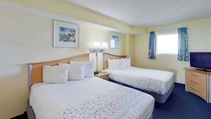 A hotel room with two beds, a television, a desk, and a window with curtains. - Bay Watch Resort 1007 (North Myrtle Beach)