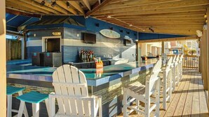 An outdoor bar area with a pool table, seating, and a bar counter. - Bay Watch Resort 1007 (North Myrtle Beach)