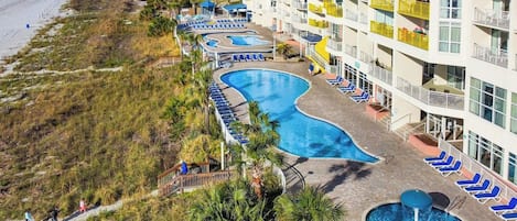 A resort with a swimming pool, beach access, and a high-rise building with balconies.