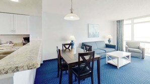 Ein modernes Hotelzimmer mit Essbereich, einer Couch, einem Couchtisch und Blick auf die Stadt.