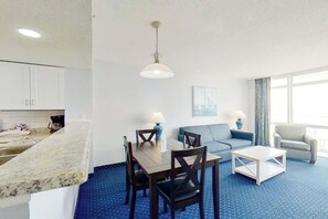 Ein modernes Hotelzimmer mit Essbereich, einer Couch, einem Couchtisch und Blick auf die Stadt.