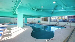 Piscina interna com água cristalina, marcação de profundidade de um metro e dezessete centímetros e vista para o exterior através de amplas janelas.