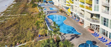 A resort with a swimming pool, beach access, and a multi-story building with balconies.