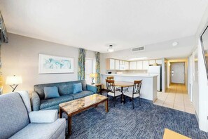 A modern living room with a sofa, coffee table, and dining area. - Bay Watch Resort 1209 (North Myrtle Beach)