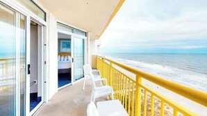 Ein Balkon mit Blick auf das Meer, ein Bett mit weißer Bettwäsche und ein geländer.