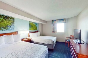 Habitación de hotel con dos camas, un escritorio con televisor y una ventana con cortinas.