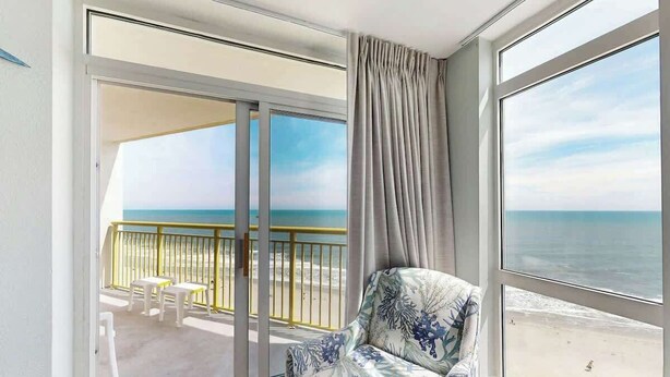Een balkon met uitzicht op het strand, een bank en een kleine tafel.