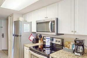 Eine Küche mit einem Edelstahl-Kühlschrank, einer Mikrowelle, einem Backofen und einer Kaffeemaschine.