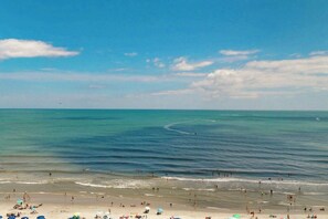 A beach with people and umbrellas, a clear sky, and a calm sea. - Bay Watch Resort 1020 (North Myrtle Beach)