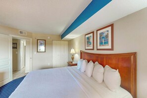 Ein Hotelzimmer mit einem großen Bett, einem hölzernen Kopfteil, einem Nachttisch mit Lampe und zwei gerahmten Bildern an der Wand.