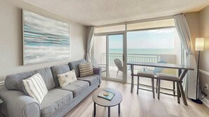 Een moderne woonkamer met een bank, salontafel en uitzicht op de oceaan door grote ramen.