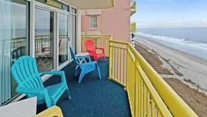 Ein Balkon mit Blick auf den Strand, mit einem blauen und einem roten Stuhl.
