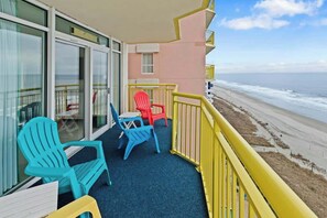 Ein Balkon mit Blick auf den Strand, mit einem blauen und einem roten Stuhl.