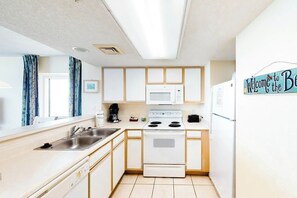 A compact kitchen with white appliances, a sink, and a microwave. - Bay Watch Resort 1022 (North Myrtle Beach)