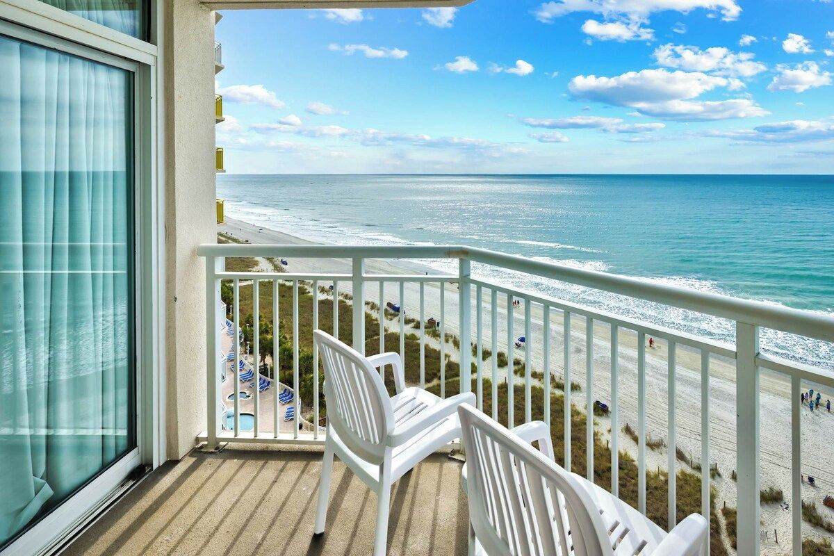 A balcony with a view of the beach and ocean.