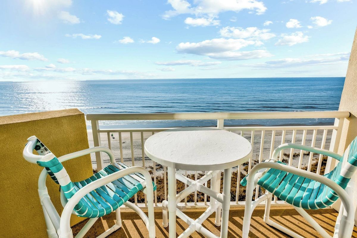 Un balcon avec vue sur l’océan, comprenant deux chaises et une petite table.