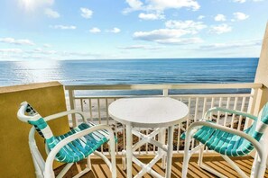 A balcony with a white table and two chairs, overlooking a beach and the ocean. - Bay Watch Resort 1038 (North Myrtle Beach)