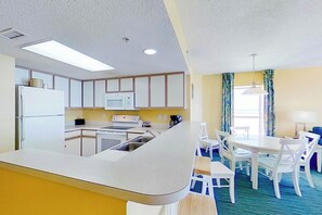 Eine kleine Küche mit Mikrowelle, Herd und Kühlschrank. Es gibt eine Essecke mit Tisch und Stühlen.