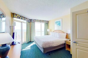 Ein Hotelzimmer mit Bett, Nachttisch, Lampe und Blick ins Freie durch das Fenster.