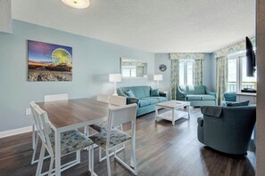 A living room with a dining table, two sofas, and a television. - Bay Watch Resort 1115 (North Myrtle Beach)
