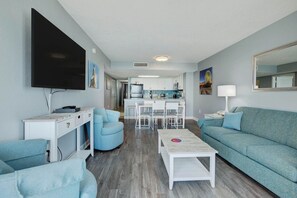 A modern living room with a sofa, a coffee table, and a TV mounted on the wall. - Bay Watch Resort 1115 Oceanfront (North Myrtle Beach)