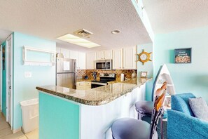 A kitchen with white cabinets, a granite countertop, and a built-in microwave. - Bay Watch Resort 1121 (North Myrtle Beach)