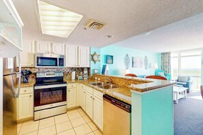 A modern kitchen with built-in appliances, a dining area with a view, and a living room with a large window. - Bay Watch Resort 1121 (North Myrtle Beach)
