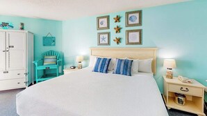 A bedroom with a bed, a nightstand, a chair, and a cabinet. - Bay Watch Resort 1121 (North Myrtle Beach)