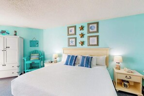A bedroom with a bed, a nightstand, a chair, and a cabinet. - Bay Watch Resort 1121 (North Myrtle Beach)