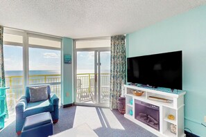 A balcony with a view, a television, and a seating area with a chair and ottoman. - Bay Watch Resort 1121 (North Myrtle Beach)