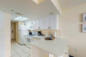 A kitchen with white cabinets, a microwave, a stove, and a sink. - Bay Watch Resort 1114 (North Myrtle Beach)