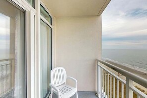A balcony with a white plastic chair, a view of the ocean, and a railing. - Bay Watch Resort 1114 (North Myrtle Beach)