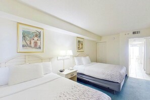 A hotel room with two beds, a nightstand, a lamp, and two framed pictures on the wall. - Bay Watch Resort 1135 (North Myrtle Beach)