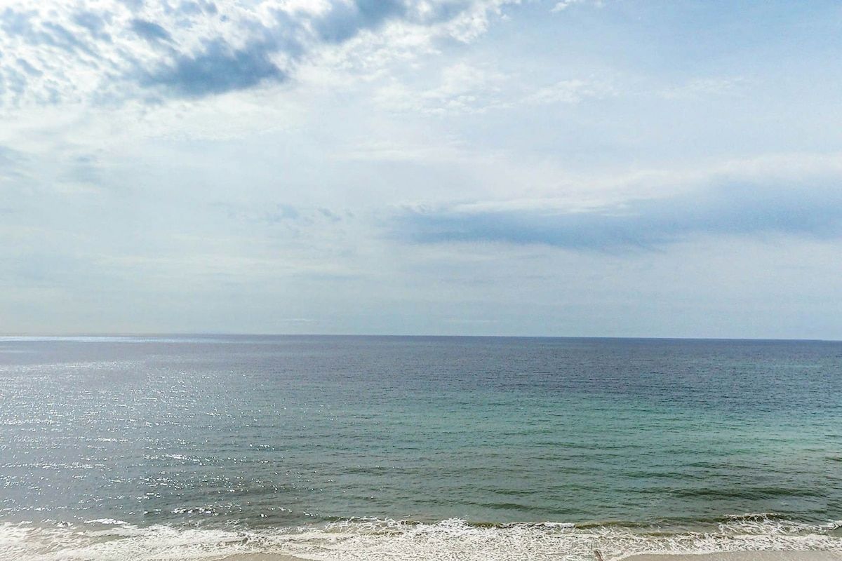Une plage avec une eau claire et un ciel nuageux.