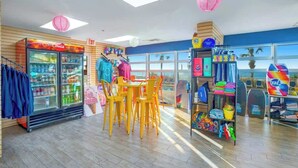 A brightly lit indoor space with a seating area, a refrigerated display case, and a variety of colorful items on shelves. - Bay Watch Resort 1139 (North Myrtle Beach)