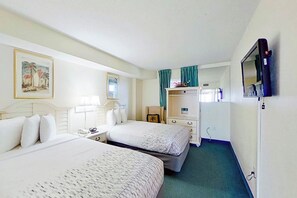 A hotel room with two beds, a desk, a chair, a television, and a painting on the wall. - Bay Watch Resort 1139 (North Myrtle Beach)