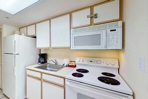 A compact kitchen with a microwave, stove, and refrigerator. - Bay Watch Resort 1139 (North Myrtle Beach)
