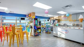 An ice cream shop interior with seating, a display case, and various items on shelves.
