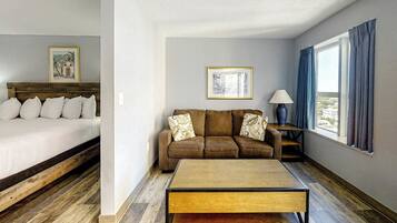A hotel room with a bed, a sofa, a coffee table, and a window with curtains.