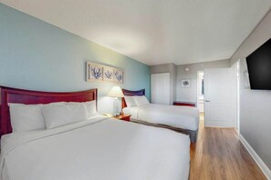 Ein Hotelzimmer mit zwei Betten, einem Nachttisch mit Lampe und einem Wandbild.