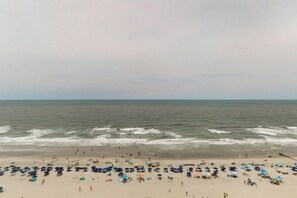A beach with numerous umbrellas and people. - Bay Watch Resort 1219 (North Myrtle Beach)