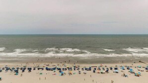 Uma praia com muitos guarda-sóis e pessoas.
