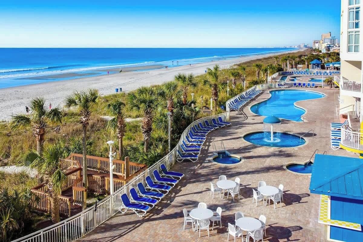Ein Resort mit Poolbereich, Liegestühlen und Blick auf den Strand.