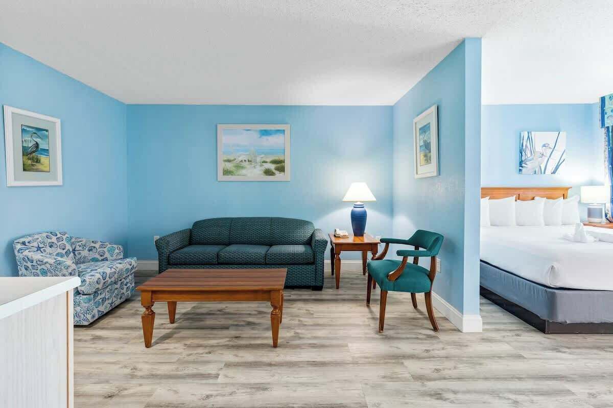 Une pièce avec un mur bleu, un lit, un canapé, une table basse et une chaise.